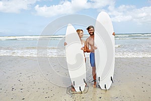 We love hitting the waves on the weekend. a young couple standing alongside their surfboards on the beach.