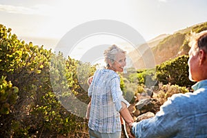 Love, holding hands and nature, senior couple walking with picnic blanket for romance and valentines day. Green mountain