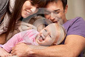 Love, hug and baby with parents in a house for playing, tickle or games while bonding in laughter. Happy family, face