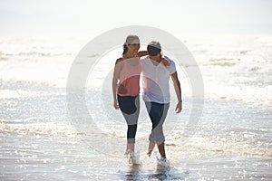 Love, hug and couple at a beach walking, calm and bonding on ocean adventure together. Travel, sunset and people at sea