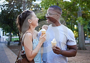 Love, ice cream or couple of friends hug in a park on a romantic date in nature in an interracial relationship. Bonding