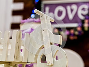 Love inscription on a wooden background, flashing lights and flowers. Close-up toy bike