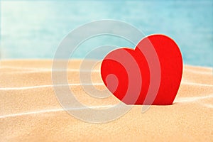 Love landscape with Red heart in sand against blue water