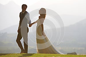 Love and laughter. A beautiful bride and groom walking hand in hand.