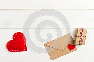 Love letter envelope with red heart and gift box on wooden background