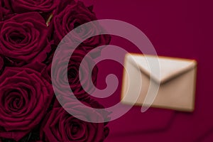 Love letter and flowers delivery on Valentines Day, luxury bouquet of roses and card on maroon background for romantic holiday