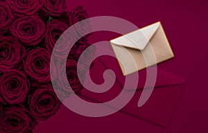 Love letter and flowers delivery on Valentines Day, luxury bouquet of roses and card on maroon background for romantic holiday