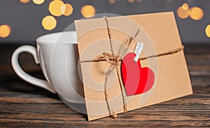 Love letter with a heart next to a cup on a background of lights  love and valentine concept on a wooden table