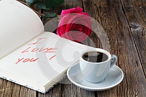 Love letter notepad, red roses and coffee cup on wooden table. Valentines day concept