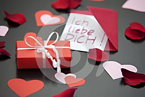 Love letter saying I love you in German and a red wrapped parcel.