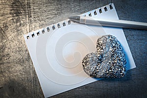 Love letter template on paper with pen and stone heart on wooden rustic desk, photo