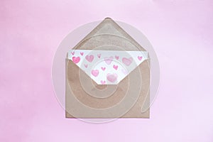 Love letter with water color pink hearts in a craft envelope on pink background