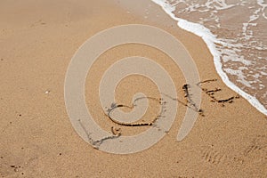 Love lettering on the sandy beach and sea water