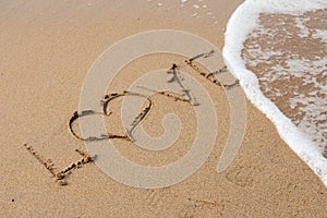 Love lettering on the sandy beach and sea water