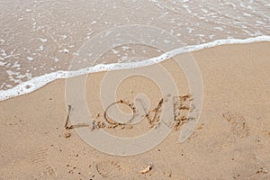 Love lettering on the sandy beach and sea water