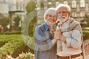 Love is life. Portrait of cheerful happy senior couple bonding to each other and holding hands while standing in the