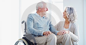 Love is a lifelong commitment. a senior man in a wheelchair being cared for by his wife.