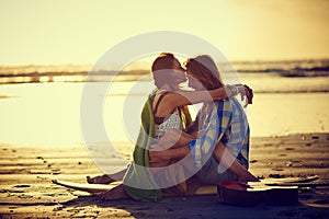 Love is like an ocean, deep and always in motion. a couple sitting on the beach with their legs intertwined.