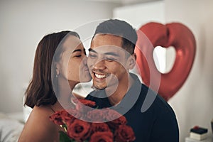 Love lives here. Shot of a young woman kissing her husband on the cheek at home.