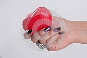 Love for manicure art concept. Beauty hands holding red heart shaped jewelry box. Stylish pastel burgundy velvet gel Nails