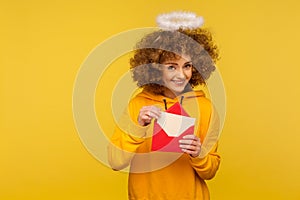 Love message. Portrait of happy curly-haired angelic woman with saint nimbus holding letter in envelope