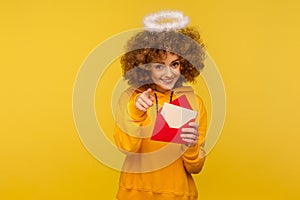 Love message. Portrait of pretty curly-haired angelic woman with saint nimbus holding letter envelope