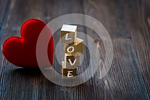 Love message written in wooden blocks with red heart, old wood background.