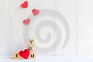 Love message written in wooden blocks with red heart, white wood background.