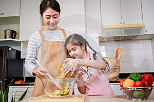 Love moment of Asian family mom and daughter helping preparing vegetable salad in kitchen at home