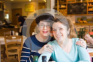 Love of mother and daughter. Happy women in a nice cafe with copy space on blurred background. Aged woman and her adult