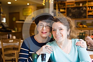 Love of mother and daughter. Happy women in a nice cafe with copy space on blurred background. Aged woman and her adult