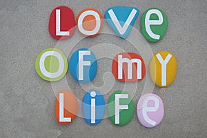 Love of my life, creative message composed with multi colored stone letters over beach sand
