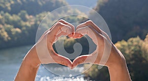 Love nature, travel, Earth day concept. Heart made by women hands, backgroubd of beautiful mountain landscape. Panoramic