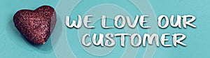 we love our customer concept with heart toy on blue background.