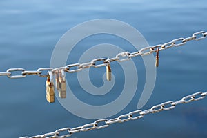 Love padlocks hanging on metal chain fence