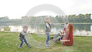 Love and parenthood concept. Happy Family with children blow soap bubbles outdoors