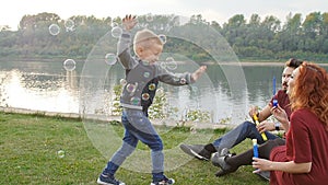 Love and parenthood concept. Happy Family with children blow soap bubbles outdoors