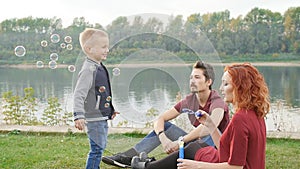 Love and parenthood concept. Happy Family with children blow soap bubbles outdoors