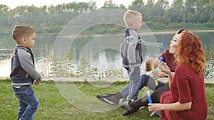 Love and parenthood concept. Happy Family with children blow soap bubbles outdoors