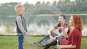 Love and parenthood concept. Happy Family with children blow soap bubbles outdoors