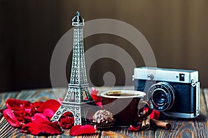 Love Paris! Rose, vintage camera, Eiffel tower, coffee cup, chocolate and cinnamon sticks on wooden background. St Valentine`s Day