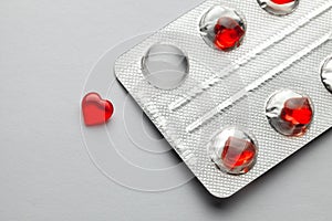 Love pills. Blister pack with red heart shaped pills. Tablets for lovers or potency. Gray background