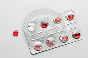 Love pills. Blister pack with red heart shaped pills. Tablets for lovers or potency. Gray background