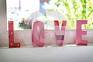 love in pink letters in front of the window photo