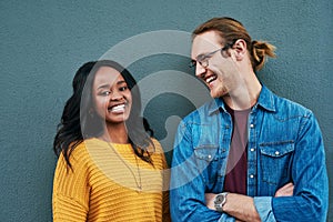 Love, portrait and happy couple laughing against a wall background, bonding and having fun. Interracial relationship