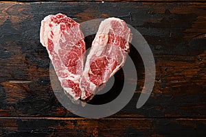 Love Raw Chuck Tenders steak on vintage dark wood table Organic beef. Black  Top view.  Space for text