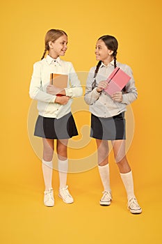 We really love reading. Small children with reading books on yellow background. Adorable little girls learn reading at