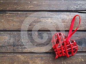 Love red wicker heart on wooden texture background. Valentines day greeting card. Top view with copy space. Red wicker