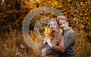 Love, relationship, family and people concept - close up of couple with maple leaf in autumn park