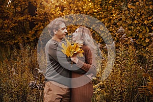 Love, relationship, family and people concept - close up of couple with maple leaf in autumn park